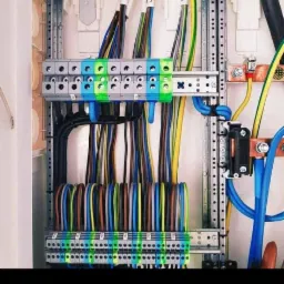 Rozdzielnica elektryczna z uporządkowanymi przewodami o różnych kolorach, zamocowanymi do listew zaciskowych; widoczne oznaczenia numerów na przewodach.
