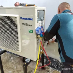 Monoblok klimatyzacji Panasonic Inverter R32 na metalowej konstrukcji, podłączony do manometrów przez instalatora w trakcie montażu na zewnątrz budynku.