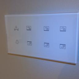 Biały touch panel do sterowania inteligentnym domem - zarządzanie oświetleniem i roletami.
