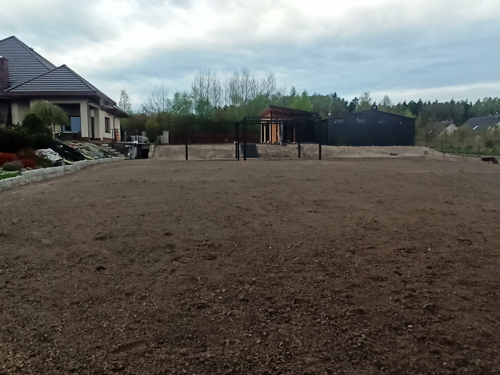 Plantowanie ziemi między budynkami. Zrobienie skarpy oraz dalsze plantowanie terenu pod trawnik.