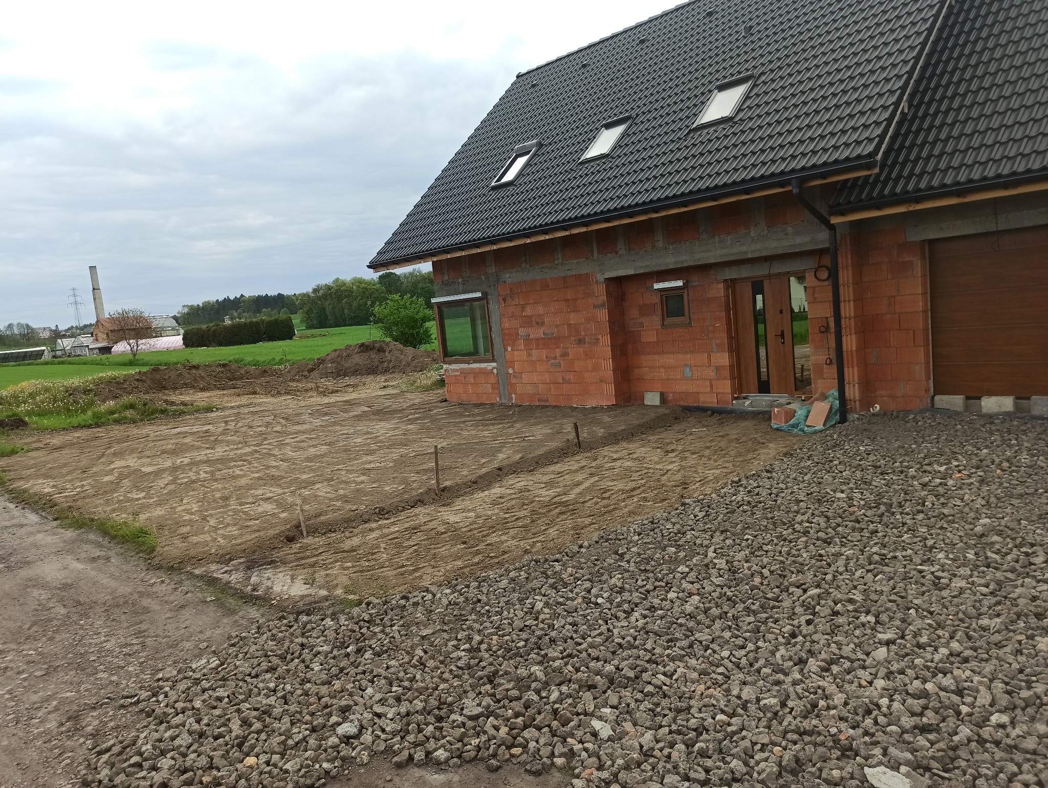 Zrobienie podjazdu pod garaż oraz pod wejście do domu. Plantowanie nadmiaru ziemi z wykopu pod dom.