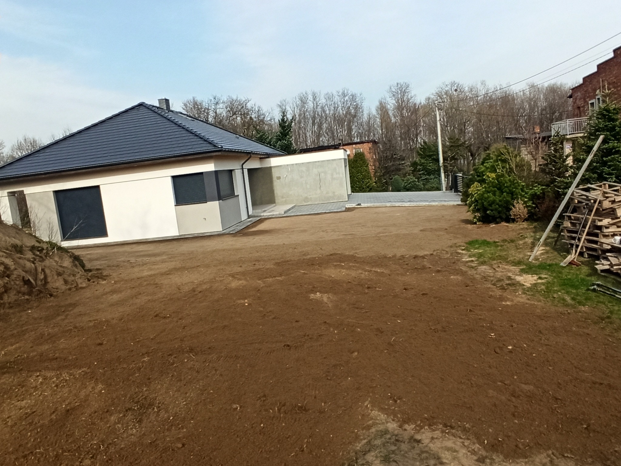 Plantowanie humusu wokół domu pod trawnik. ze spadkami w kierunku granic działki.