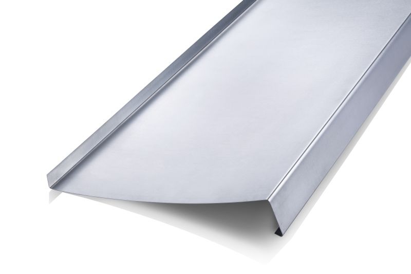 Metalowy parapet okienny o gładkiej, srebrnej powierzchni, sfotografowany na białym tle, z wyraźnie widocznymi krawędziami i załamaniami blachy.