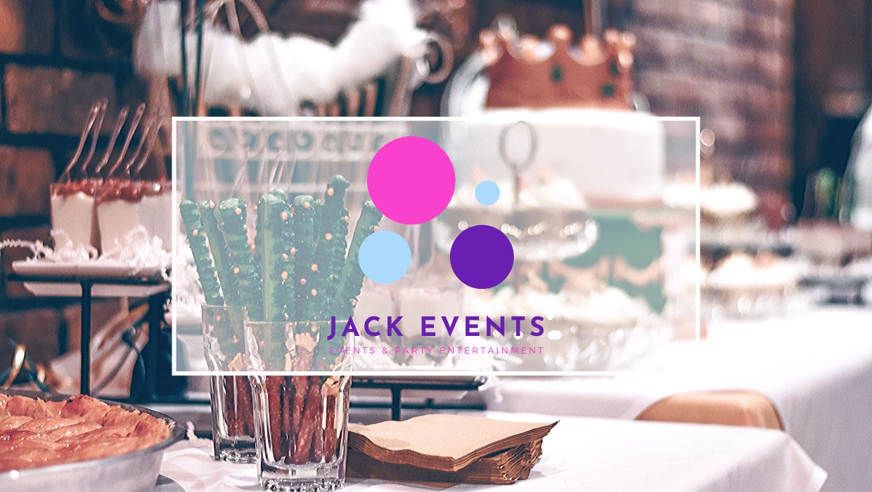 Udekorowany stół z przekąskami, ciastami i preclami w szklankach, z logo firmy eventowej na pierwszym planie.