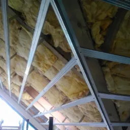 Ocieplenie poddasza wełną mineralną, widoczne metalowe profile konstrukcyjne przed montażem płyt gipsowo-kartonowych.