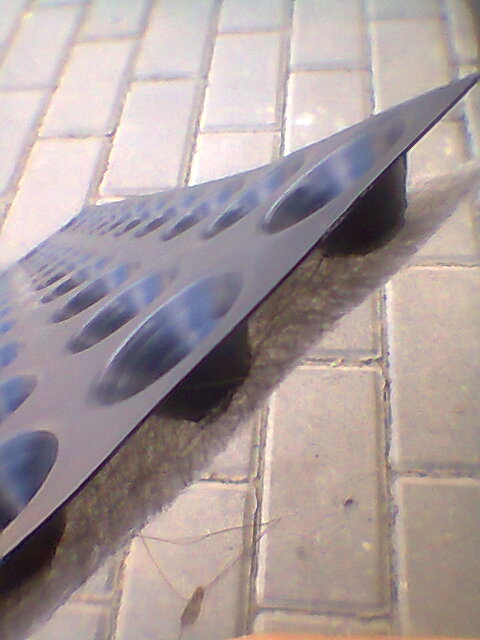 Wytłaczana geomembrana TEFOND z charakterystycznymi wytłoczeniami w kształcie elips, leżąca na szarej kostce brukowej.