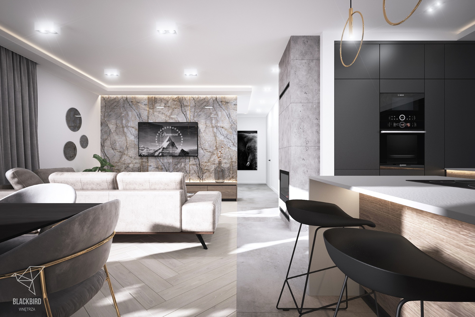 Nowoczesne wnętrze: salon z marmurową ścianą, telewizorem i sofą, płynnie przechodzący w kuchnię z czarnymi szafkami i wyspą z hokerami.