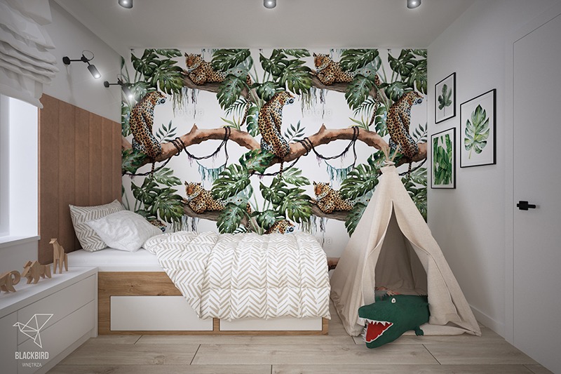 Pokój dziecięcy z łóżkiem, tipi i tapetą w dżunglę z motywem leopardów, drewniane figurki zwierząt na komodzie, oświetlenie punktowe.