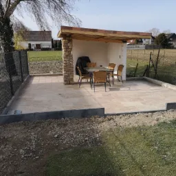 Zadaszony taras z kamienną kolumną i meblami ogrodowymi w Bolesławcu, widok na ogród i okoliczne domy.