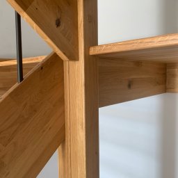 ELBOWOOD Andzej Borkowski - Fragment drewnianych schodów z balustradą, ukazujący detale konstrukcyjne i naturalne usłojenie drewna dębowego. Widoczne połączenia elementów i minimalistyczny design.