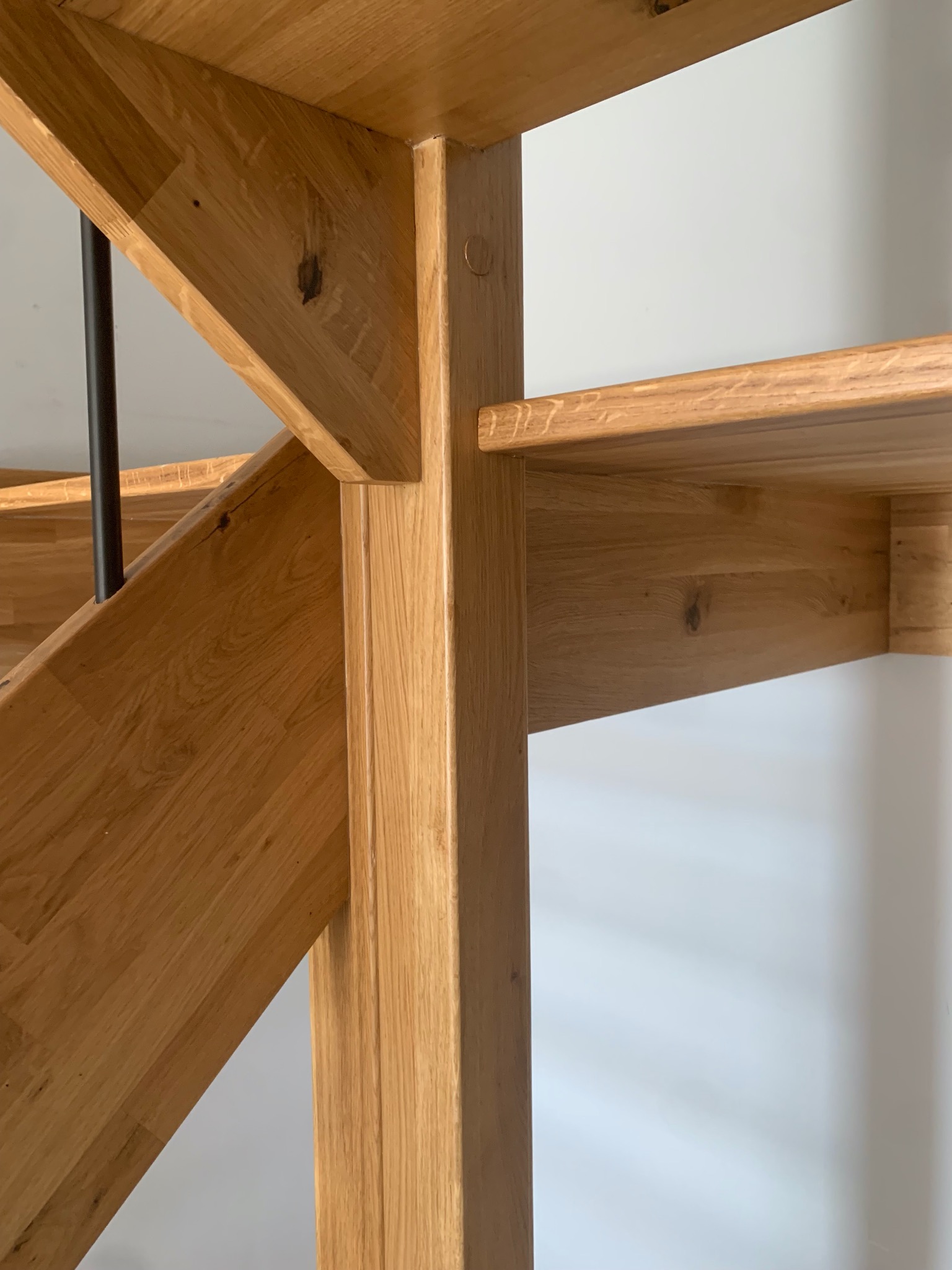 Fragment drewnianych schodów z balustradą, ukazujący detale konstrukcyjne i naturalne usłojenie drewna dębowego. Widoczne połączenia elementów i minimalistyczny design.