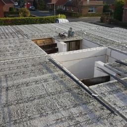 Staska Bau Rem - Surowy strop Teriva z widocznym zbrojeniem i pustakami szalunkowymi, przygotowany do zalania betonem, na tle zabudowy jednorodzinnej.