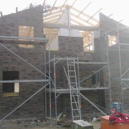 Staska Bau Rem - Budowa domu jednorodzinnego w trakcie murowania ścian z cegły klinkierowej, widoczne rusztowania i konstrukcja dachu.