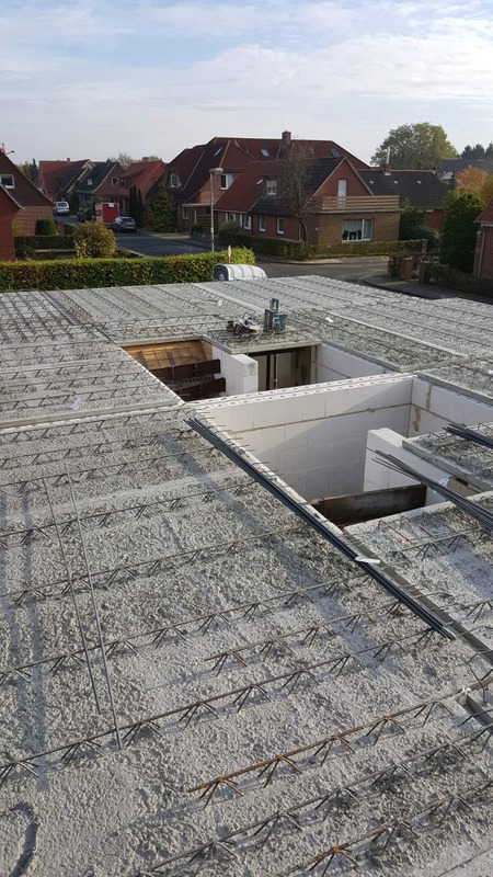 Surowy strop Teriva z widocznym zbrojeniem i pustakami szalunkowymi, przygotowany do zalania betonem, na tle zabudowy jednorodzinnej.