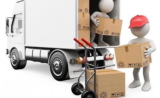 Animowane postacie ładują kartony do białej ciężarówki, wózek transportowy z dwoma kartonami na pierwszym planie.