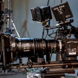 Profesjonalna kamera filmowa RED Epic-W z obiektywem ARRI Alura Zoom 18-80, zamontowana na statywie, z widocznymi monitorami podglądowymi i akcesoriami, ustawiona w zacisznym studiu filmowym.