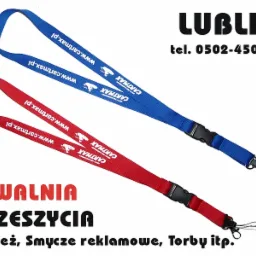 Dwa smycze reklamowe: czerwony i niebieski, z logo firmy Cartmax i adresem strony internetowej, na białym tle z informacją o przeszyciach odzieży w Lublinie.