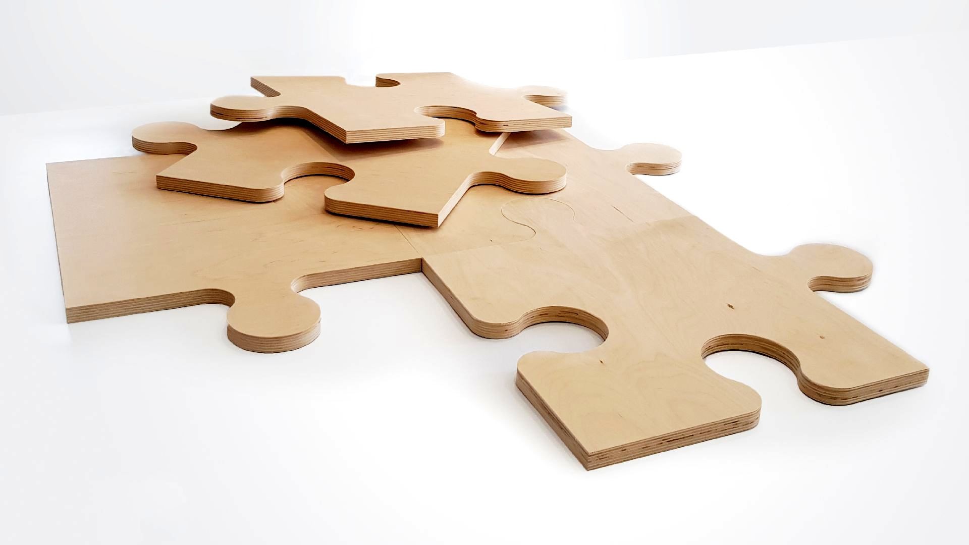 Wycięte ze sklejki elementy układanki puzzle, widoczne warstwy sklejki, jasne tło.