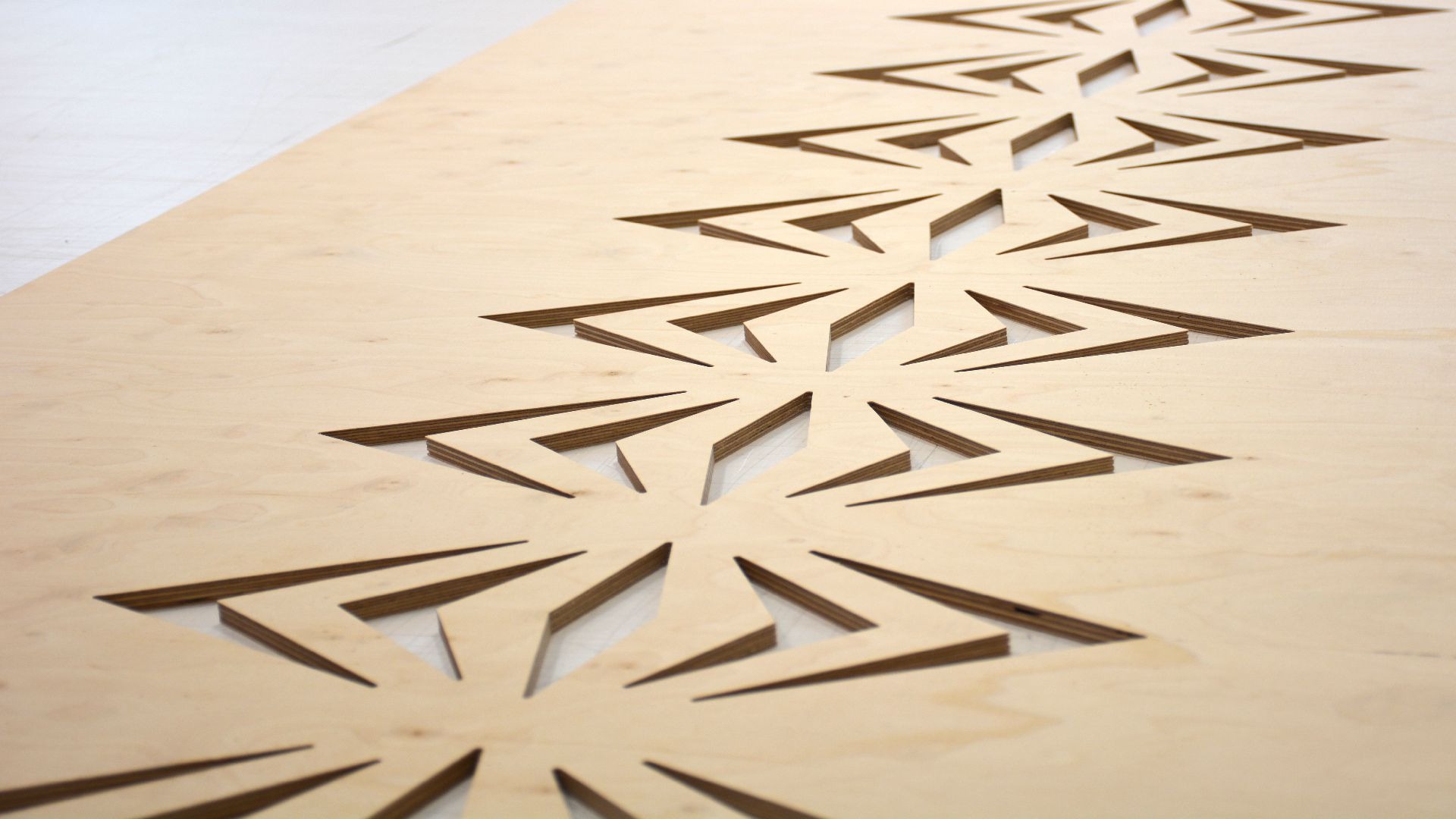 Płyta ze sklejki z wyfrezowanym wzorem w kształcie gwiazd, widoczne warstwy sklejki w krawędziach cięcia.