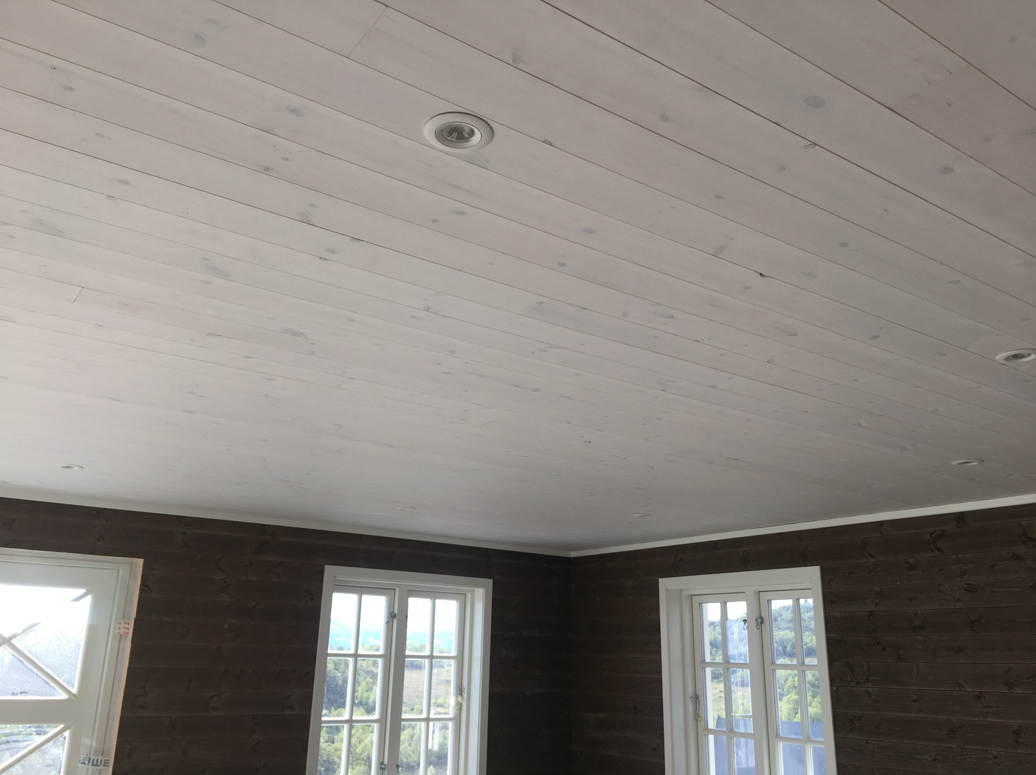 Wnętrze domu w Radomiu z drewnianą boazerią na ścianach i suficie pomalowanym na biało z wbudowanymi punktowymi lampami.