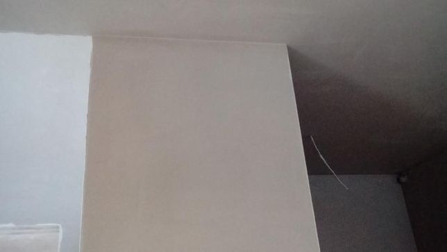 Wykończony narożnik ścian po tynkowaniu maszynowym, widoczna gładka powierzchnia i przejście do sufitu.