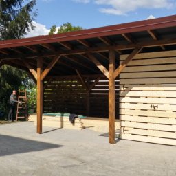 Usługi Ciesielsko-Dekarskie - Drewniana altana z brązowym dachem w trakcie budowy, widoczne dwie osoby na drabinach i część konstrukcji z desek.