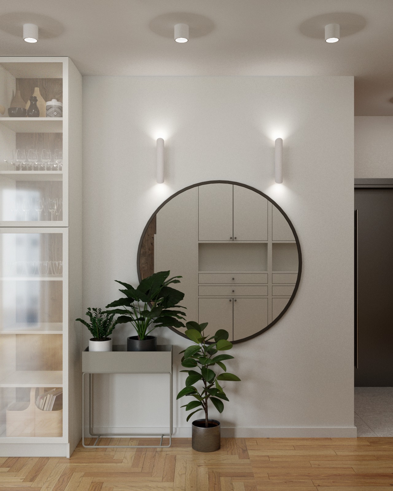 Jasne wnętrze z okrągłym lustrem odbijającym zabudowę, roślinami doniczkowymi i witryną z dekoracjami, oświetlone kinkietami.