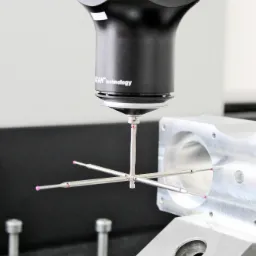 Precyzyjny pomiar detalu maszynowego za pomocą 3-osiowej maszyny pomiarowej Renishaw SP600Q z głowicą dotykową i trzpieniami pomiarowymi z rubinowymi końcówkami, ustawionej na granitowej płycie...