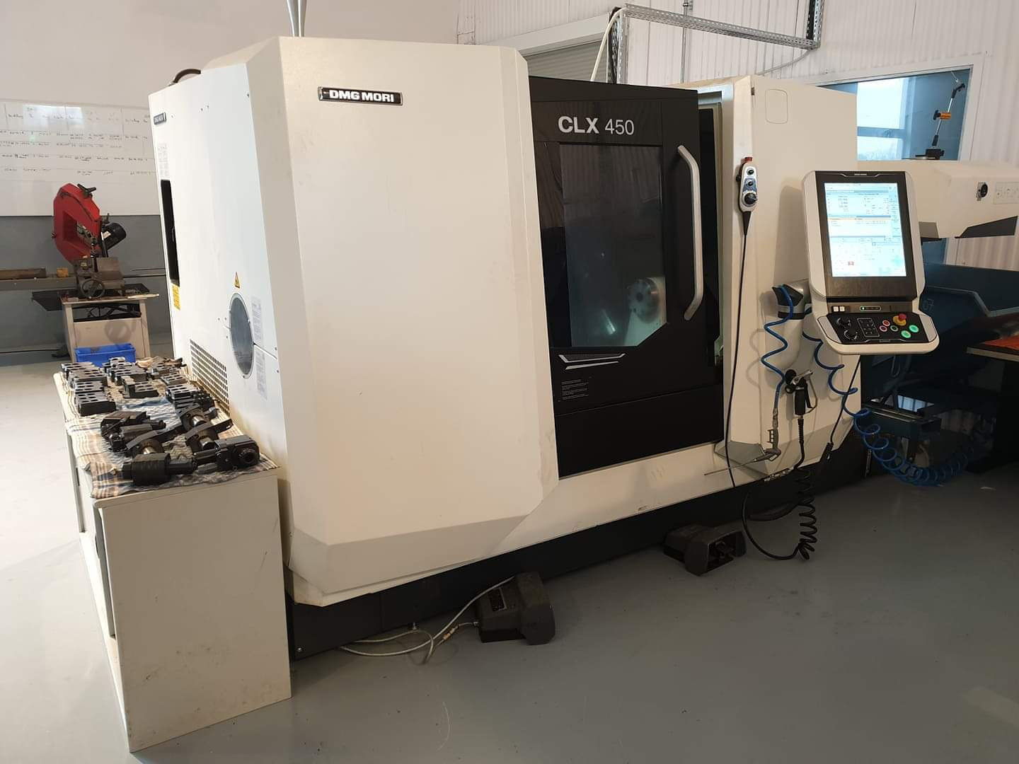 Tokarko-frezarka DMG Mori CLX 450 w hali produkcyjnej, z widocznym panelem sterowania i detalami obróbki na stole obok.