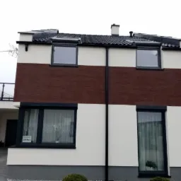 Dwukondygnacyjny dom z elewacją w pasy: biały tynk i brązowa struktura, czarne rynny i okna z roletami zewnętrznymi, widok z zewnątrz.