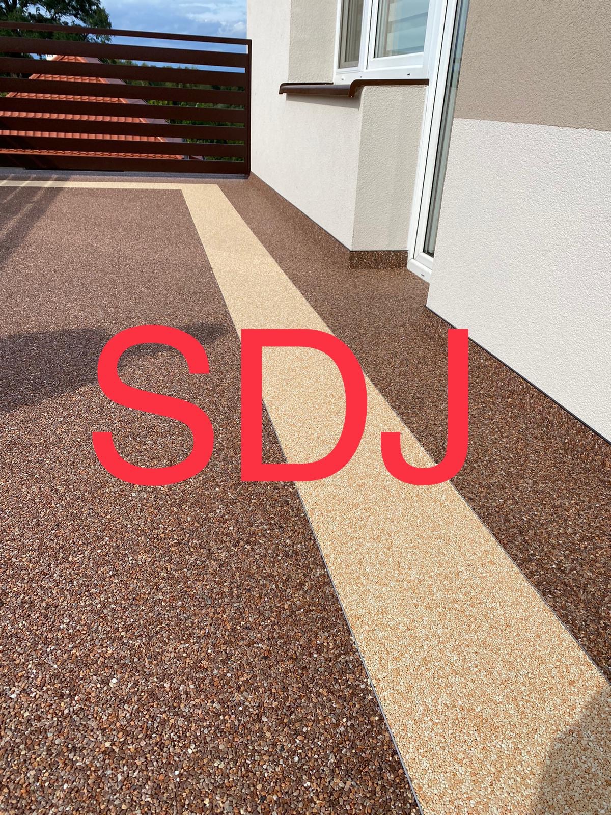 Balkon z żywicznej posadzki z dekoracyjnym pasem w odcieniach beżu i brązu, widok z góry na fragment balustrady i elewację budynku.