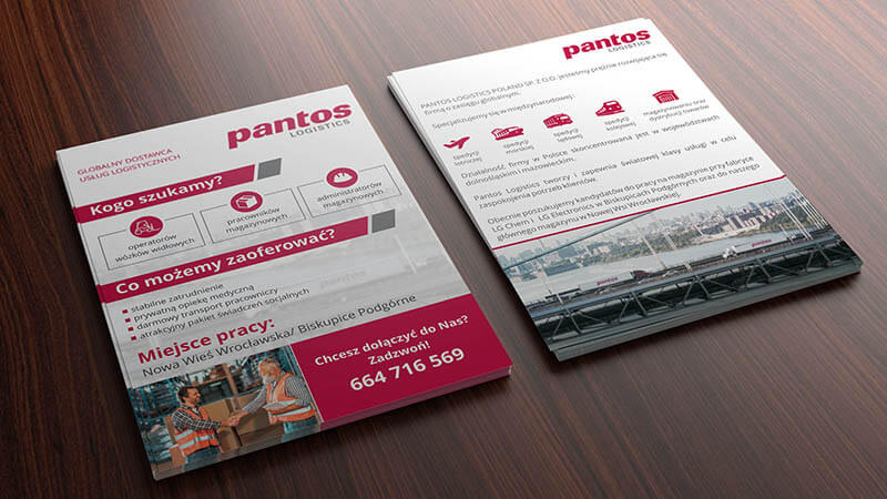 Dwie ulotki firmy Pantos Logistics na drewnianym stole, prezentujące ofertę pracy dla operatorów wózków widłowych i pracowników magazynowych, z informacją o stabilnym zatrudnieniu i prywatnej...