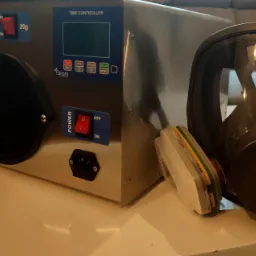 Generator ozonu z maską ochronną na stole, widoczne przełączniki mocy i timer.