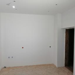 Hadson - Wnętrze pokoju po świeżym malowaniu na biało, z widocznymi puszkami elektrycznymi i przygotowanym otworem okiennym, podłoga wyłożona płytami OSB.