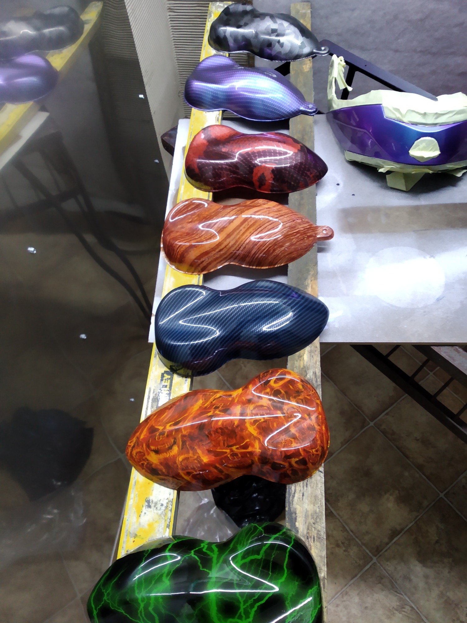 Różnorodność wzorów hydrografiki na elementach karoserii samochodowej: kamuflaż, fioletowy karbon, czerwone plamy, drewno, niebieski karbon, płomienie i zielone błyskawice.