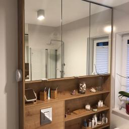 Przepis na kuchnie - Nowoczesna łazienka z szafką z lustrami i drewnianymi półkami, widoczne akcesoria łazienkowe i elementy dekoracyjne