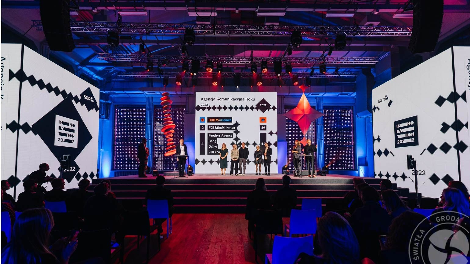 Gala wręczenia nagród Agencji Komunikacyjnej Roku na scenie z telebimami, oświetleniem i publicznością, z widocznym rankingiem firm.