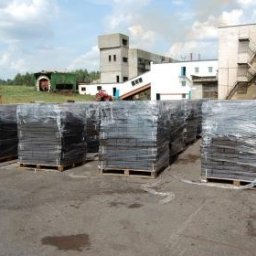 PHU BIALENERGO Olga Choińska - Sztaple brykietu drzewnego, owinięte folią i ułożone na paletach, zlokalizowane na placu firmy w Choroszczy. W tle budynki przemysłowe i fragment zieleni.