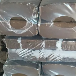 Stos pakowanych bloków ciemnej ziemi ogrodowej z wyciętymi otworami w folii, ułożonych jeden na drugim.