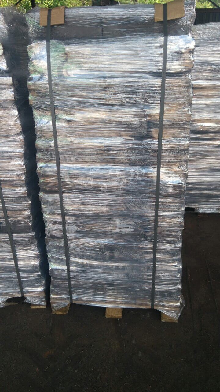 Palety z zapakowanym towarem, zabezpieczone folią i taśmą, ustawione na zewnątrz.