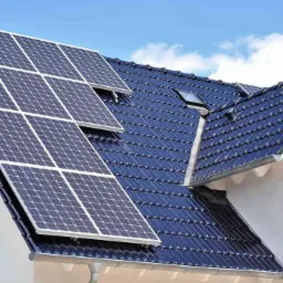 Instalacja paneli słonecznych na dachu domu jednorodzinnego w Kielcach, z widocznym oknem dachowym i ciemną dachówką.