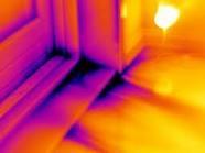 Obraz termowizyjny przedstawiający narożnik okna, ukazujący straty ciepła w postaci barw od fioletu (zimno) do żółci (ciepło). Widoczne nieszczelności w izolacji.