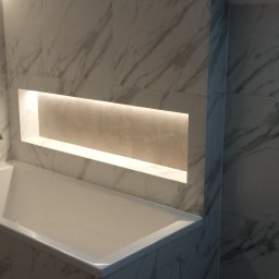 Remont4you - Biała wanna obudowana płytkami imitującymi marmur, z podświetloną wnęką w ścianie. Nowoczesna aranżacja łazienki z subtelnym oświetleniem.