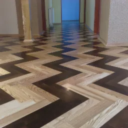 Ułożony parkiet w jodełkę w dwóch odcieniach drewna, jasnym i ciemnym, tworzący wzór na podłodze w przestronnym wnętrzu z kolumnami i otwartymi przejściami do innych pomieszczeń.