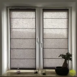 Dwa okna PCV z zamontowanymi szarymi roletami rzymskimi, na parapecie klepsydra, świeczniki i małe drzewko bonsai.