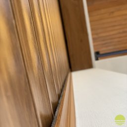 MARKIZA.PL SPÓŁKA Z OGRANICZONĄ ODPOWIEDZIALNOŚCIĄ - Fragment drewnianej konstrukcji z widoczną uszczelką i elementami montażowymi w tle, ujęcie z bliska pod kątem.