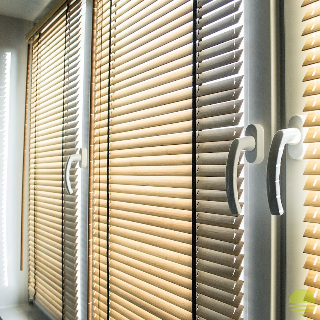 Jasne, drewniane lamele poziome w oknach z białymi ramami i uchwytami, widoczne w naturalnym świetle.