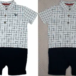 Dwu-obrazowe zestawienie niemowlęcego rampersa: biała koszula w czarną kratę z krótkim rękawem, ozdobiona małym, ciemnym haftem dinozaura i trzema brązowymi guzikami, połączona z granatowymi szortami.