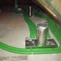 M. WENT Marek Kawka - Zielone, karbowane rury wentylacyjne w izolacji, prowadzone na poddaszu, mocowane do metalowych skrzynek.