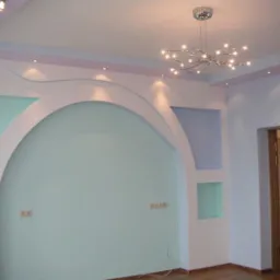 Pokój z dekoracyjną ścianą w kształcie łuku, oświetleniem punktowym i nowoczesnym żyrandolem, wykończony w pastelowych odcieniach bieli, błękitu i fioletu.